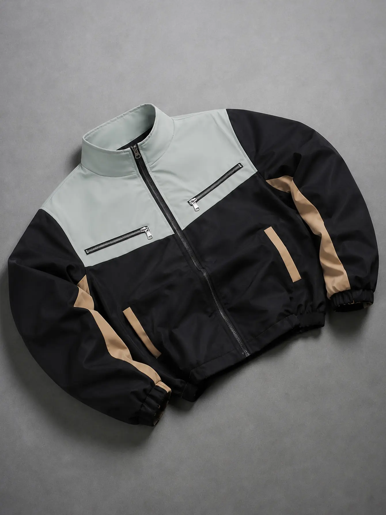 Men’s light gray-black khaki jacket with three-tone contrast, stand collar, short length, windproof design, smooth woven fabric, full zip stand collar front, dual metal zipper chest pockets, elastic cuffs and hem; suitable for street fashion and jogging o