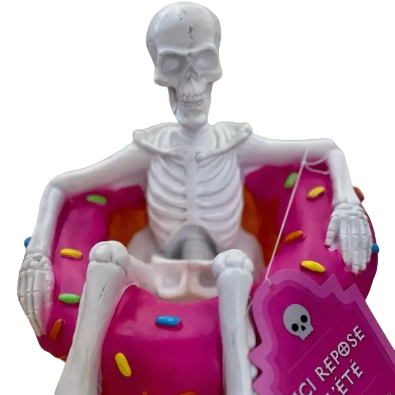 Skelleton on a pool float shaped like a donut with sprinkles