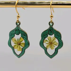 Beautiful art deco style dangle earrings. These darling earrings are an antique green in color, with tiny yellow flowers under resin in the center. Actual measurements are 1.5" long and just over a half inch wide. All products are nickel free.