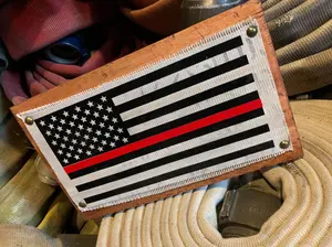 Fire hose sign for a firefighter. The heat pressed vinyl shows off the thin red line flag. The sign is made with real fire hose and is a handmade product from a small company called Crafty American