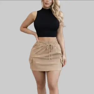 Odette Skirt - chic tan cargo mini skirt. Designed for both comfort and style, it features a flattering high-waisted fit with a functional drawstring for a customized cinch. The utilitarian-inspired cargo pockets add a touch of modern edge, Crafted from a