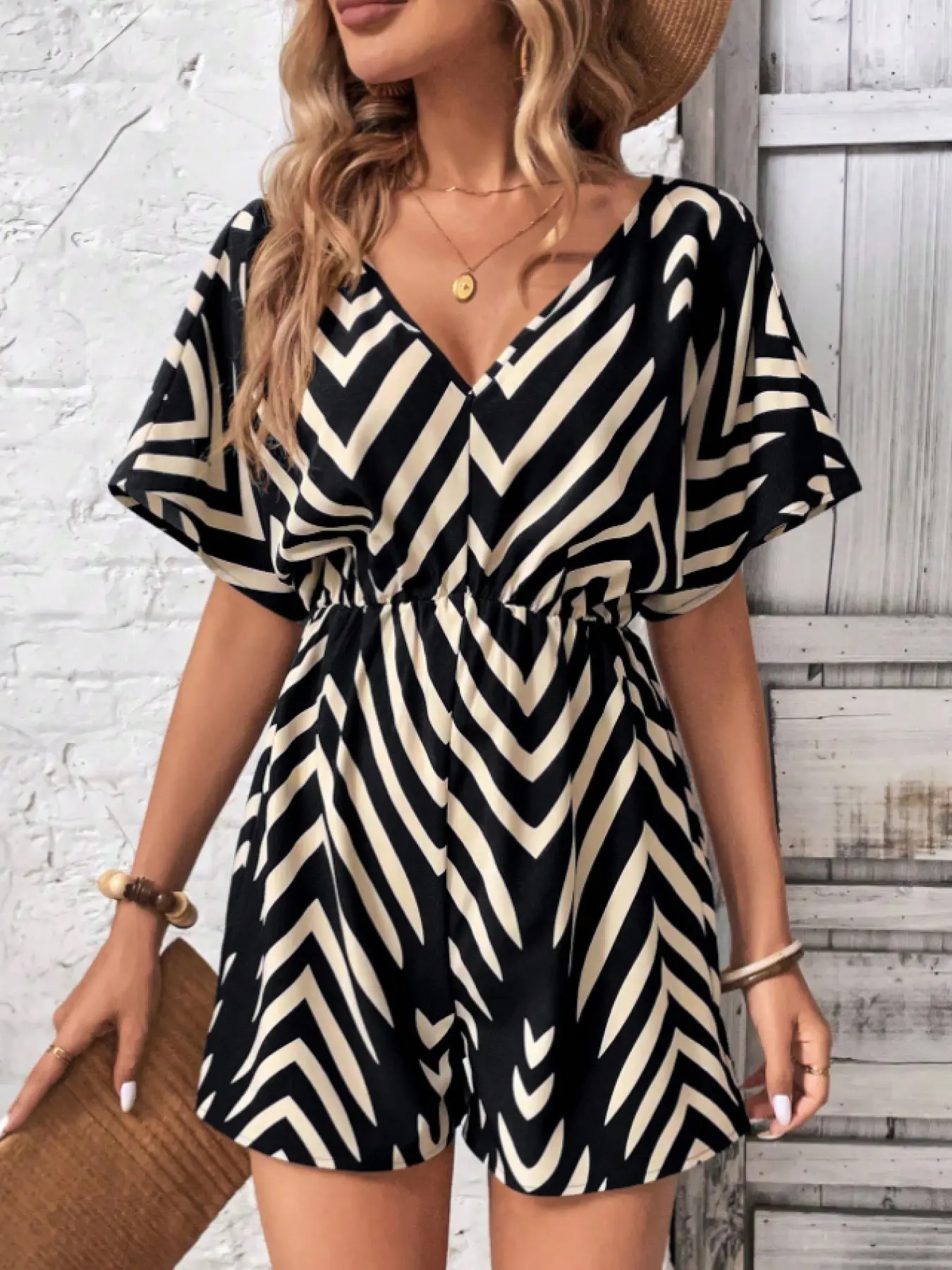 A women's black and off-white zigzag striped V-neck romper, Beach jumpsuit with puff sleeves and a cinched waist, Fitted, suitable for casual occasions like weekend outings or gatherings with friends, Striped print romper