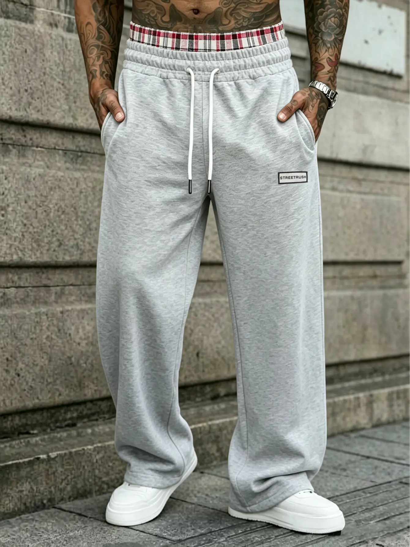 One men’s knit sweatpants in an American street style, featuring a plaid spliced waistband paired with a square fabric tag, a white drawstring elastic waistband, suitable for men when shopping, exploring shops, and going out, with a high visibility design
