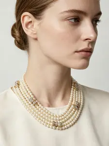 A multi-layered beige imitation pearl short choker necklace, embellished with diamond studded bow ornaments, with an elegant retro texture, suitable for commuting, light banquets, and French retro fashion scenes.