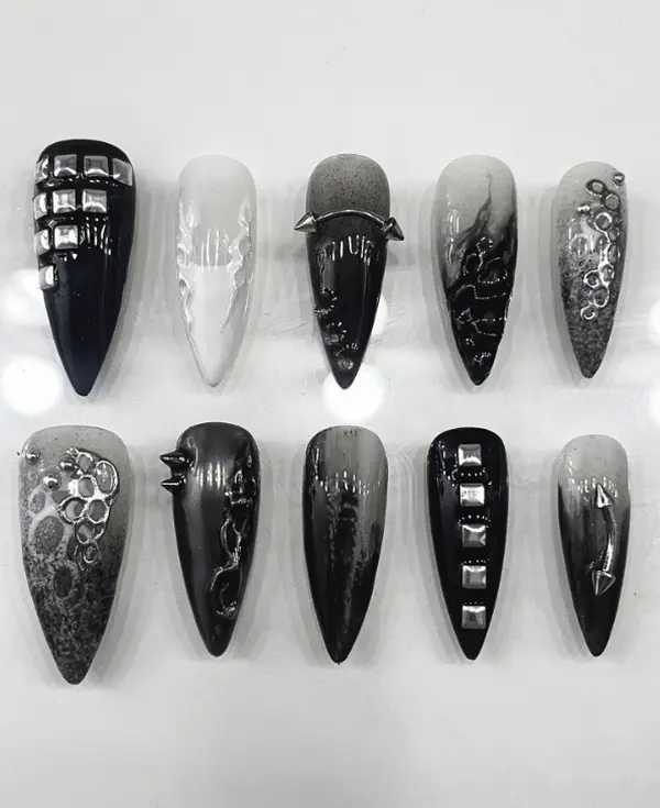 Edgy black and grey ombre nails with chrome studs, spikes, abstract molten textures, and grunge metallic detailing—perfect cyber-goth statement claws
