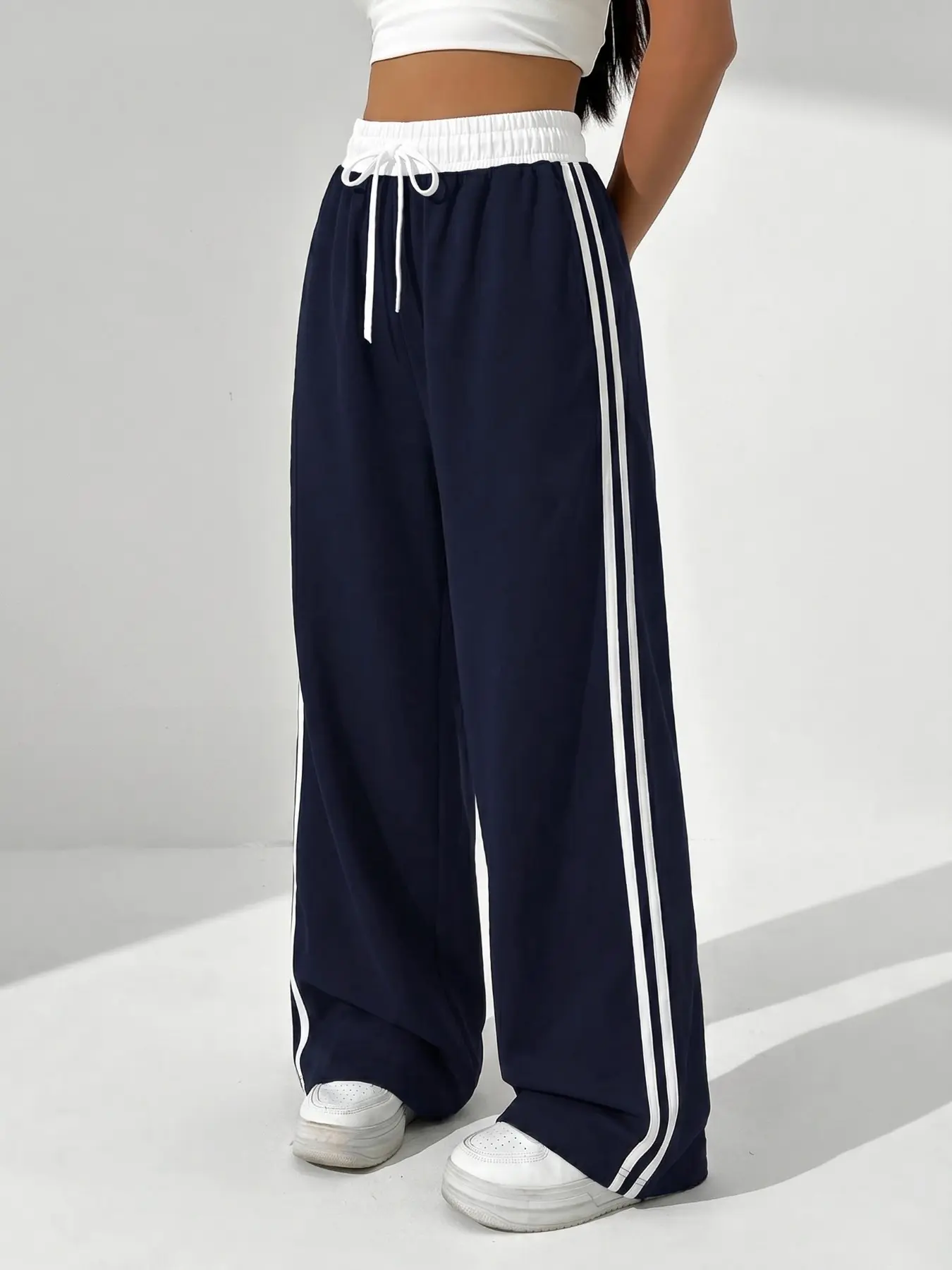 Navy Blue Side Stripe Wide-Leg Track Pants, Y2K Sporty & Casual Vibe, Casual Athletic Pants. These high-waisted wide-leg pants feature a contrast white elastic drawstring waistband and iconic double white stripes running down the sides.