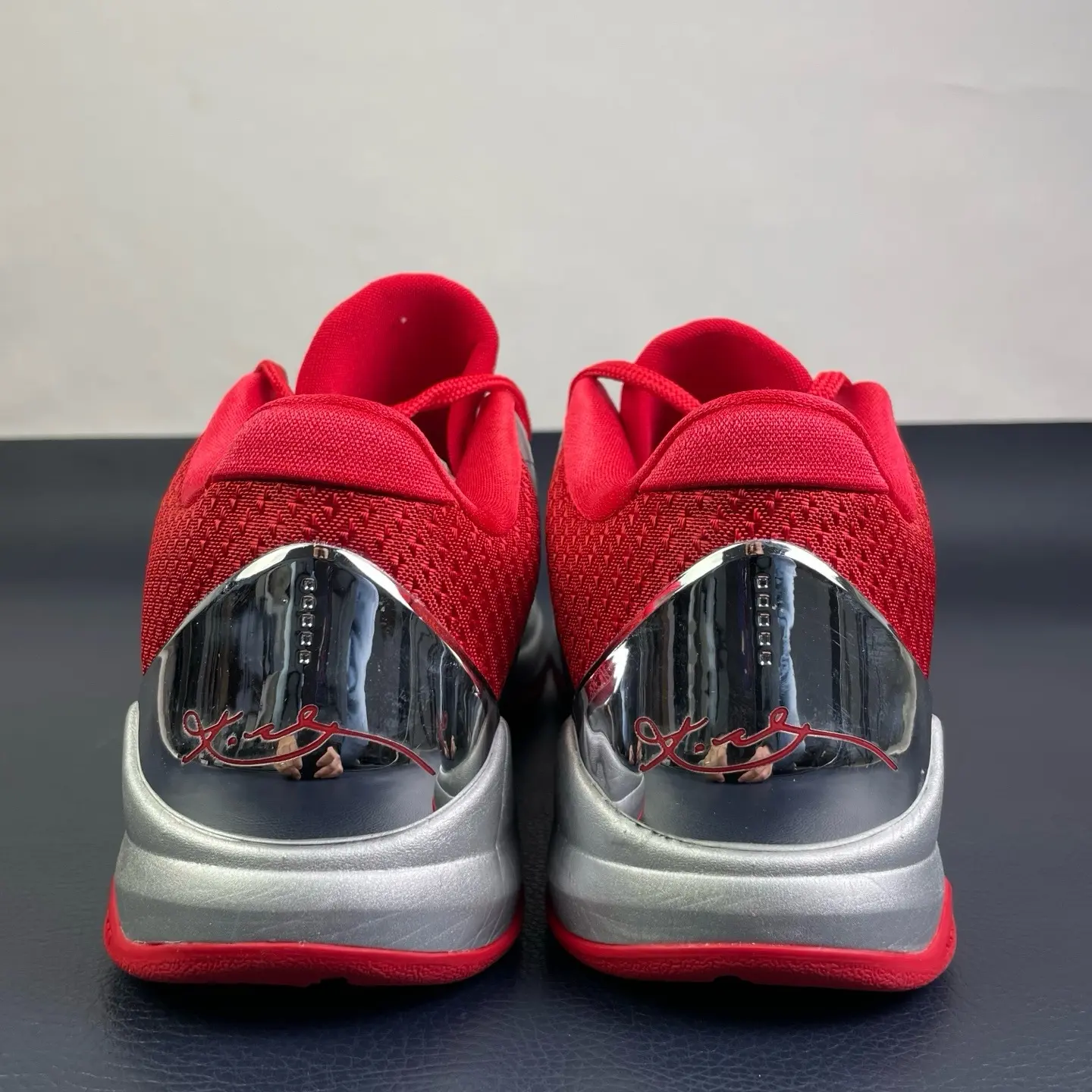 Silver‑red low‑top court shoes, smooth metallic synthetic upper, red heel lining, black laces, padded tongue, shock‑absorbing midsole for daily streetwear
