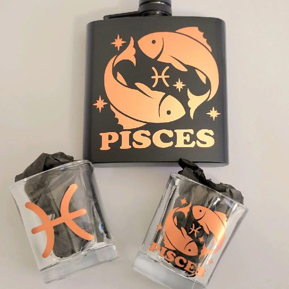 Pisces Zodiac Flask Set – Rose Gold Edition Product Highlights  - Includes: 1 Pisces flask (6 oz), 2 square shot glasses (2 oz each), 1 mini funnel   - Rose gold metallic detailing with Pisces glyph, fish symbol, and star accents   - Matte black stainless