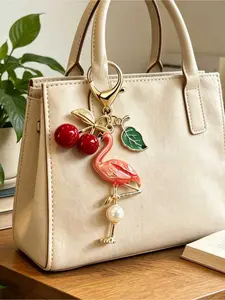Gold-plated flamingo bag charm with pearl inlay and cherry leaf accents. Bohemian & Hawaiian tropical style, also works as keychain. Versatile decor for bags, purses, earphone cases and cars.