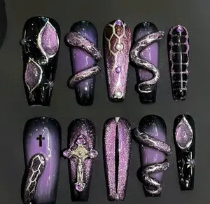 Dark purple and black nails with glitter snakes, crosses, and gemstone accents – a bold gothic manicure with mystical, edgy allure.