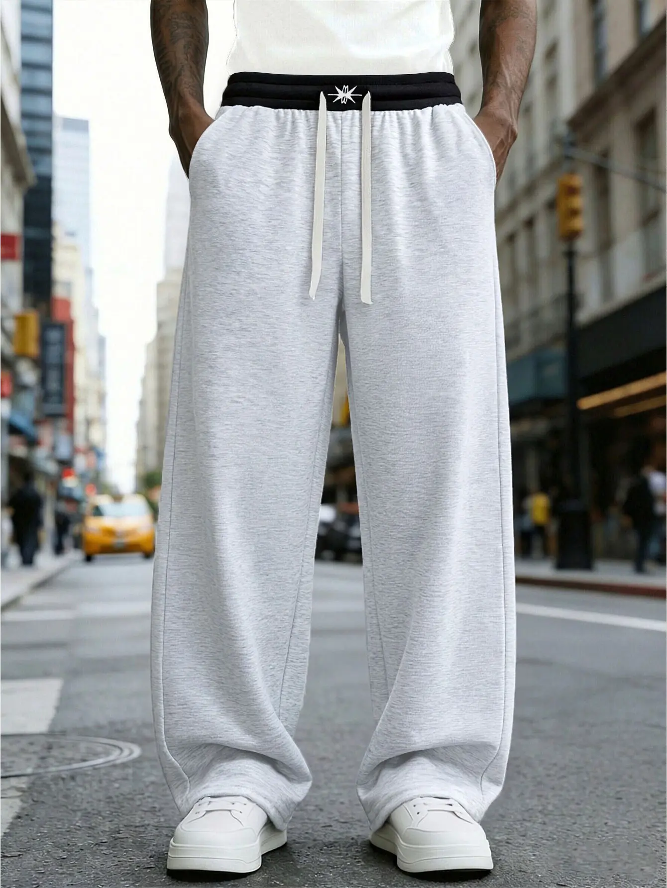 A pair of loose and fashionable sports trousers for men, with an outward-turned waistband and a color-blocked design. The wide-leg trousers are casual and simple, with a tie at the waist and large pockets, suitable for daily walks, work, travel, etc