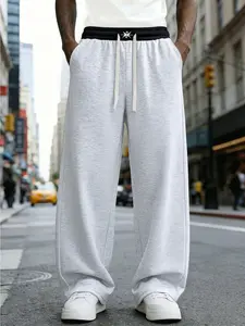 A pair of loose and fashionable sports trousers for men, with an outward-turned waistband and a color-blocked design. The wide-leg trousers are casual and simple, with a tie at the waist and large pockets, suitable for daily walks, work, travel, etc