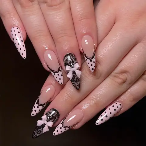 24-Piece Set of Long Almond Acrylic Press On Nails — Y2K "Sweet & Edgy" Style Decorative Nails. Featuring a dark aesthetic with black polka dots and lace-patterned French tips, these fake nails are accented by a light-luxury nude-pink bow design