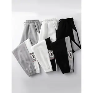 Men’s sweatpants with side stripes and a patched drawstring waist; casual carrot pants with an elastic waistband and pockets for spring and fall; fashionable men’s bottoms for everyday wear