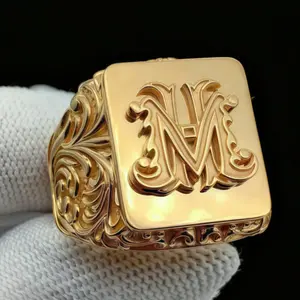 An elegant 18K gold-plated square ring with a classic embossed "M" handwritten motif, a piece of jewelry for men and women.