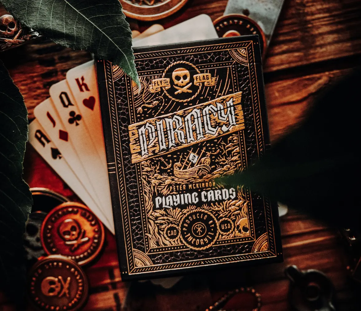 Theory11 Piracy Playing Cards - Premium 2.5" x 3.5" Deck for 12 Years Above, Custom Artwork, Custom Gold Tuck Seal, Dual-Foil Printing, FSC-Certified Paper, Adventure-Themed Card Game, Cardists, Fully Custom Back Design, Ace Coin Art, Gold Foil Courts, 2‑