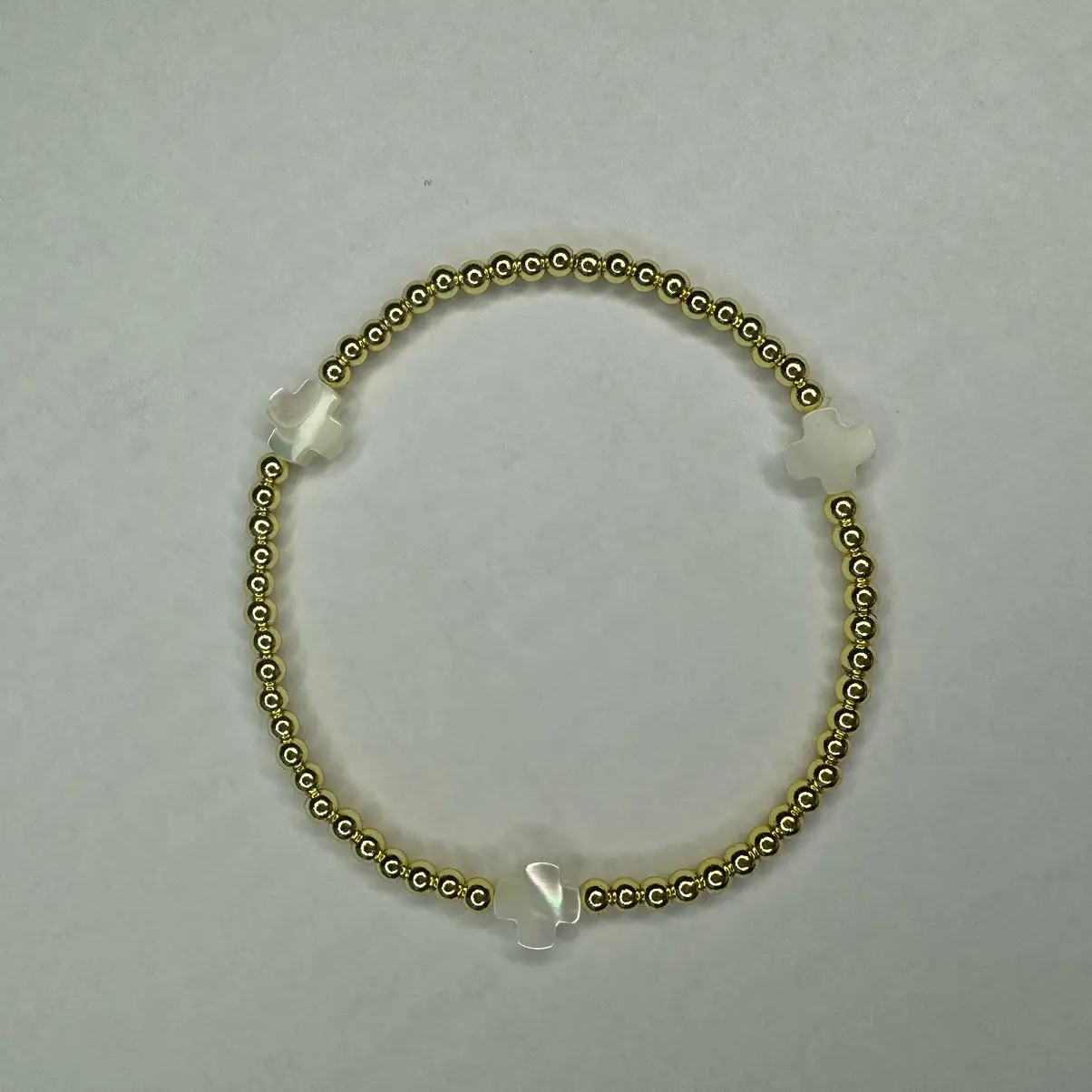 The Glow bracelet CROSS - 6.5” stretchy bracelet Made with: 3mm round gold plated hematite beads with 8mm white color mother of pearl cross beads