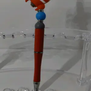 orange platic glitter ink pen with a orange rocket food grade silicone focal bead. Accented with blue and gray round food grade silicone beads. With black ink and a extra black ink refill.