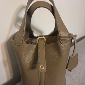 Elegant Taupe Leather Bucket Bag with Gold Hardware and Detachable Strap for Versatile Use