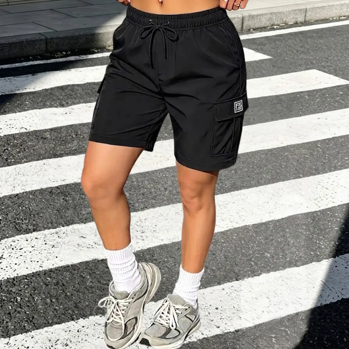 Women’s polyester fashion cargo shorts made from quick-dry, lightweight fabric. Elastic drawstring waist with flap side cargo pockets and a small square logo tag. Wrinkle-resistant, loose casual fit—ideal for streetwear, hiking, and everyday wear. Availab