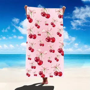 An Oversized Microfiber Bath Towel Featuring a Cherry Blossom Design, Perfect for The Beach Or Pool. It Has a Pink Base Adorned with Vibrant Red Cherries And a White Bow. Ideal for Activities Like Yoga, Travel, Surfing, And Camping