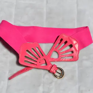 women's Pink elastic waist belt featuring a decorative, laser-cut brown faux leather bow buckle. 2 Inches Wide One Size: