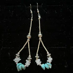 A pair of Navajo handmade sterling silver hook earrings featuring liquid silver beads, silver plated rose buds, silver daisy-shaped beads, smokey white quartz, and magnesite turquoise.