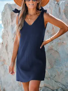 A women's navy blue V-neck sleeveless short dress with shoulder straps and bow decoration, suitable for seaside strolls, Beach, summer outdoor picnics. Comfortably loose and exudes vacation and leisure Casual wear