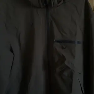 Men’s softshell lightweight windproof hooded jacket with drawstring design, sporty casual style, large front pocket, side zip closure, suitable for spring and autumn, back-to-school season outfits, long-sleeve version ideal for outdoor wear in spring and