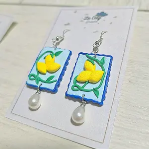 handmade polymerclay earrings feature a lemkn design on a rectangular shape light blue background