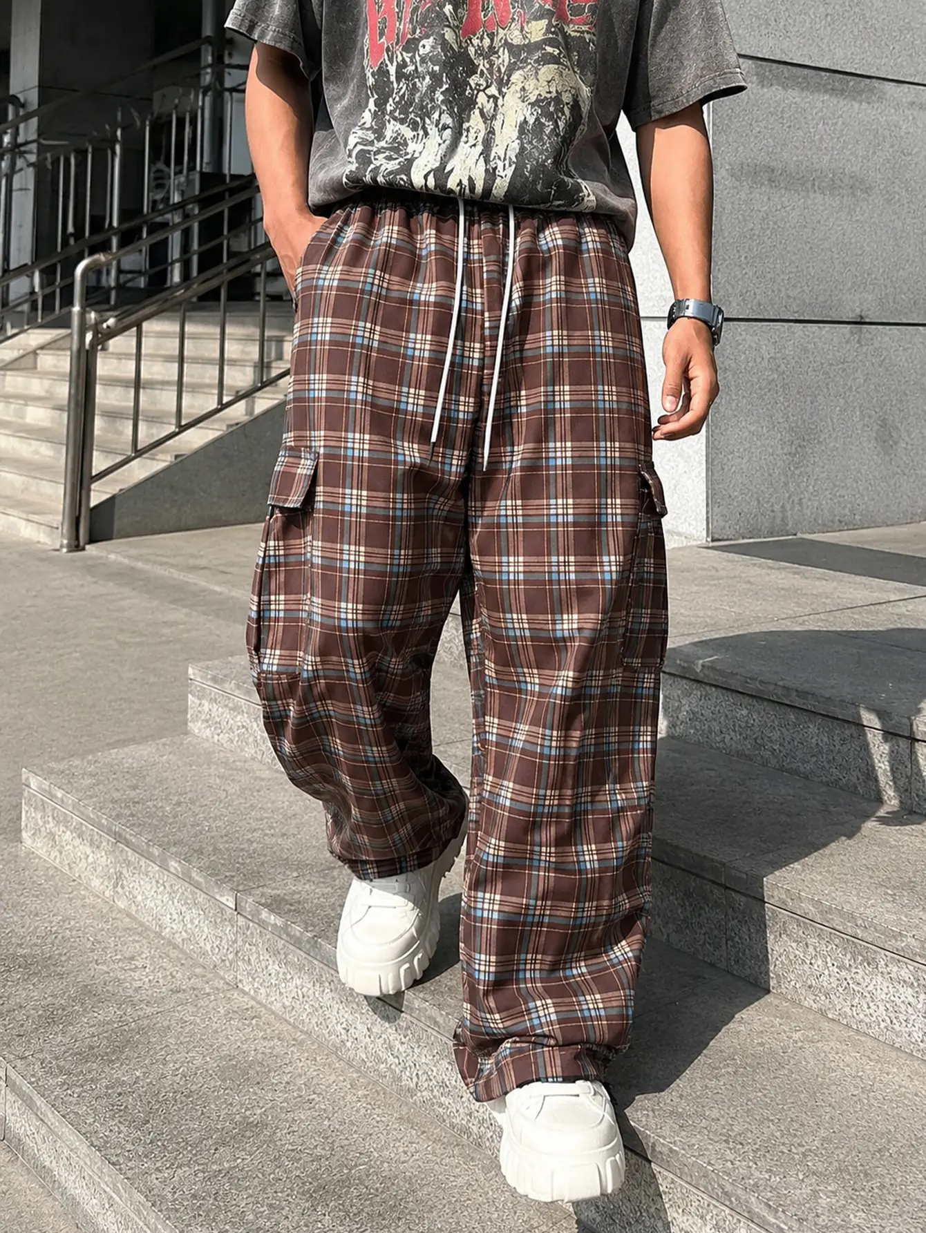 Men’s brown-coffee plaid wide-leg cargo pants featuring a drapey plaid fabric, an elastic adjustable drawstring, side utility pockets, a loose straight floor-length fit, versatile plaid pants in a retro campus street style.