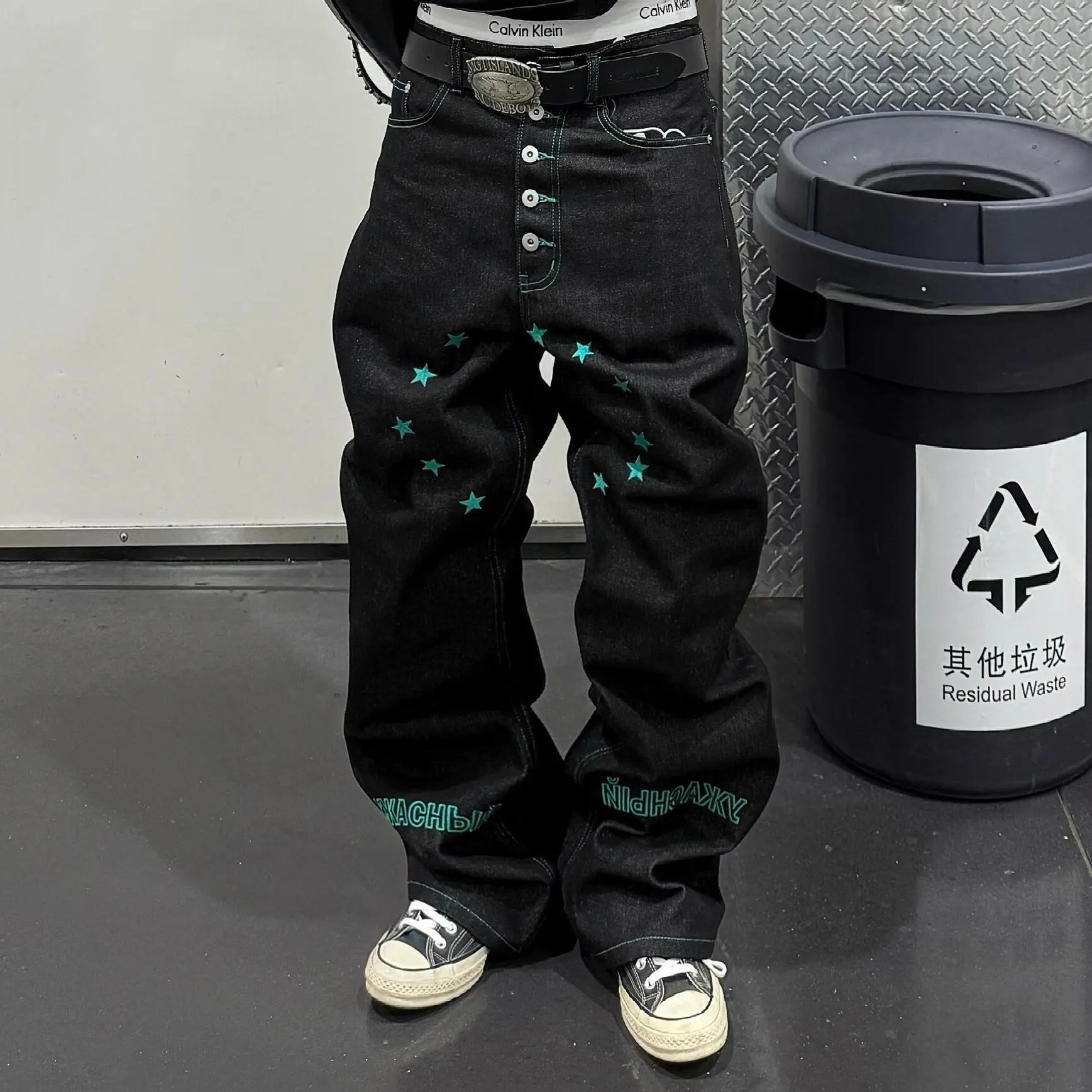 Men’s raw black flared wide-leg jeans with green star embroidery, multi-button fly, contrast stitching, denim street pants