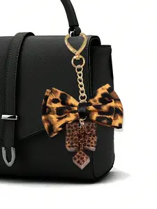 Fashionable leopard print bow and gold heart design keychain pendant, bag charm, stylish backpack charm, bag accessory, leopard print bow, heart-shaped spring clip, gold heart pendant, suitable for hanging on bags, pants, backpacks, and crossbody bags.