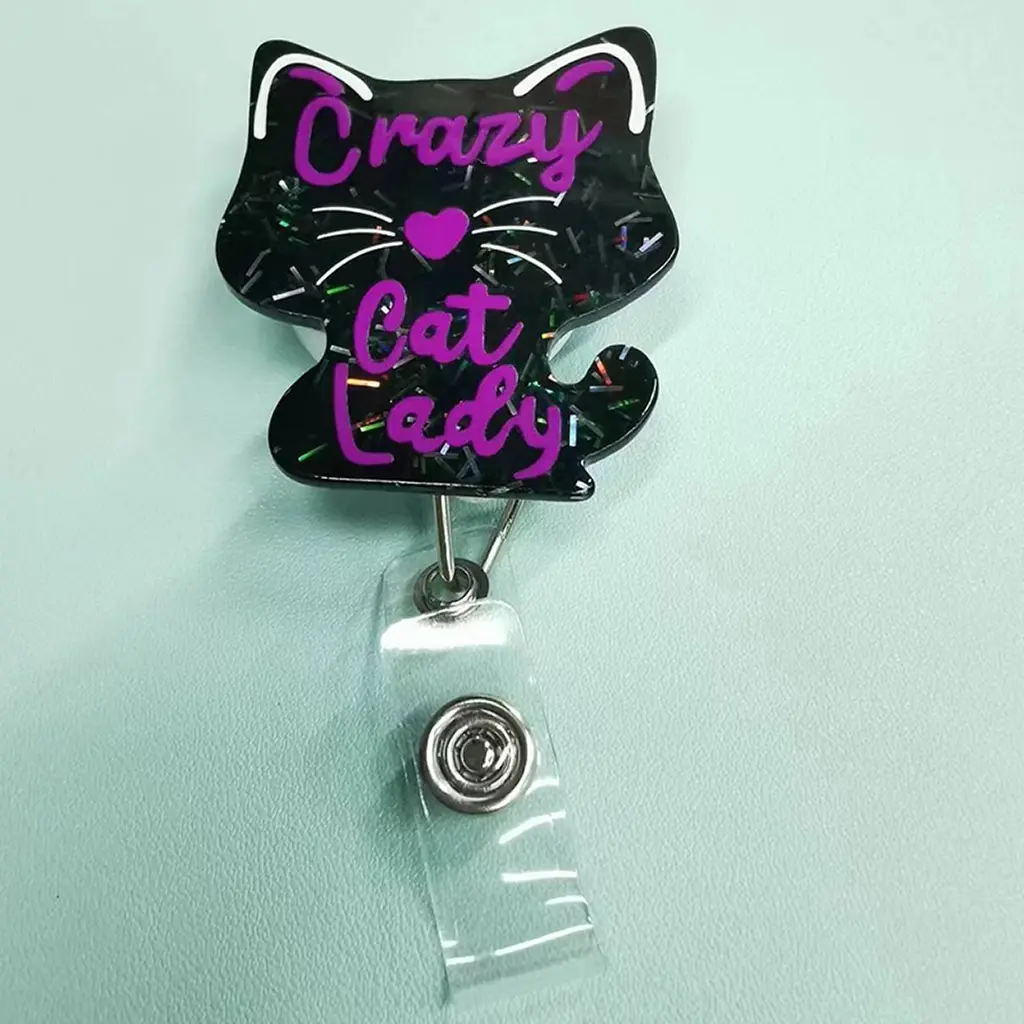 A cat-shaped work brand retractable buckle, the main body is designed with black glitter, with purple text "Crazy Cat Lady" and purple love decoration; equipped with retractable structure and transparent card clip