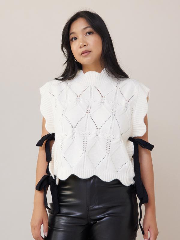 Wishlist Vest - White comfy cable knit sweater vest with scallop details, black side bows, and a turtleneck, offering a slightly oversized fit