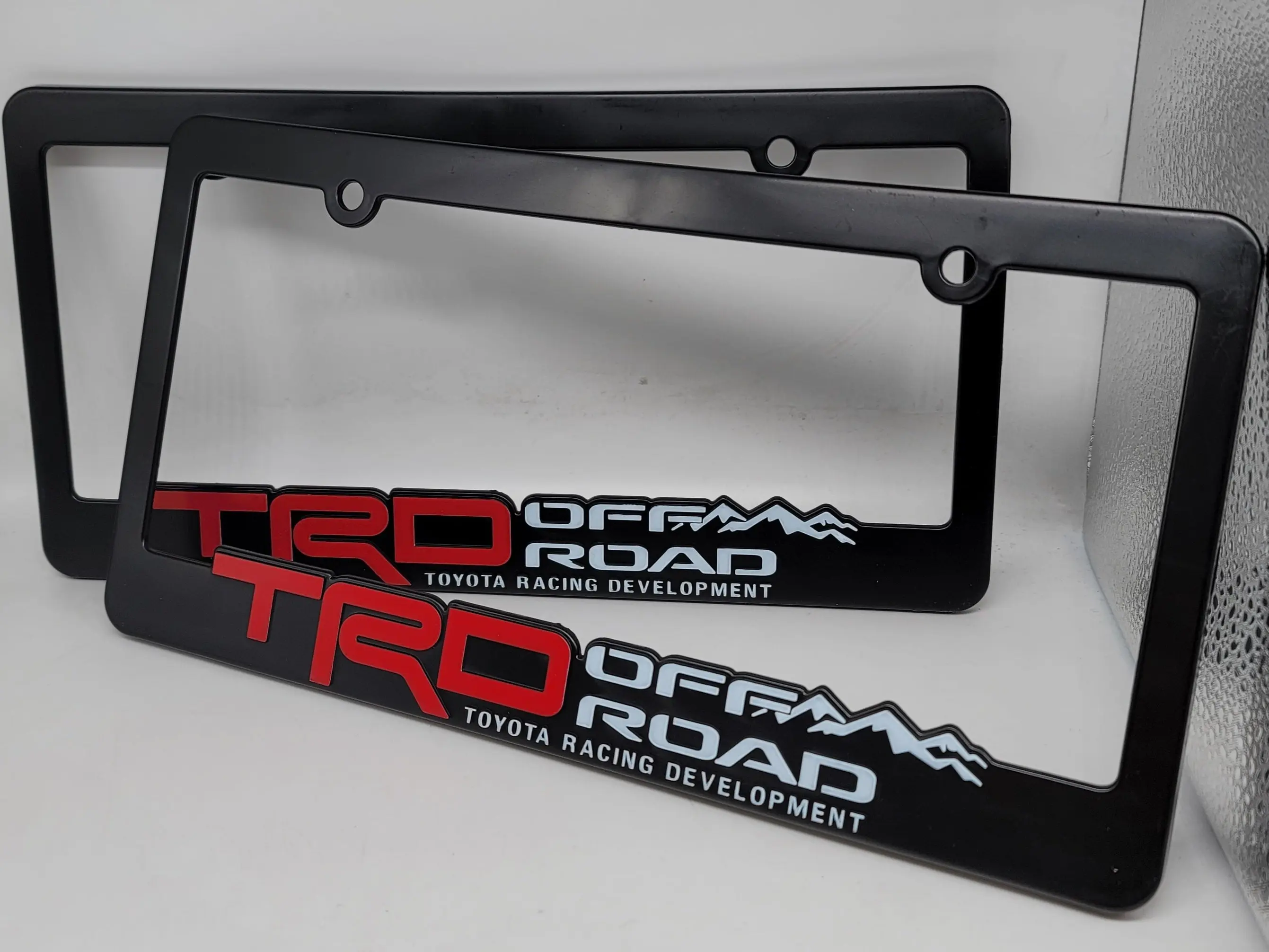 2-pack 3D embossed ABS license plate frames, glossy black truck exterior modification parts, available in TRD Sport and TRD Off-Road styles, compatible with Toyota Tacoma, Tundra, and 4Runner