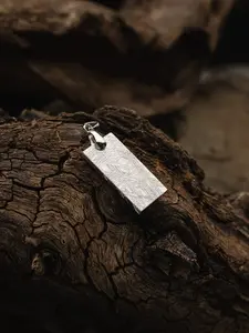 A meteorite pendant in the shape of a rectangle.