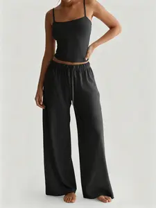 Women’s two-piece set available in multiple colors: slim-fit spaghetti-strap short top with a one-shoulder neckline that shows the waist + drawstring high-waisted wide-leg pants made from highly elastic, skin-friendly fabric with a drapey feel. Solid basi