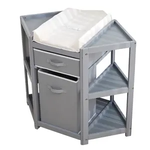 Save space with this gray corner baby changing table. It has a pull-out fabric drawer, a laundry hamper, and a waterproof pad. Sturdy pine frame with safety straps.
