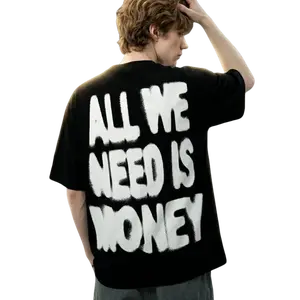All We Need Is Money Graffiti Graphic T-Shirt. Black oversized short streetwear tee with bold spray paint print. High street hip hop aesthetic, trendy fashion, TikTok viral essential for gym & casual wear.