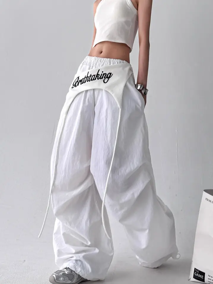 Y2K double-layer cargo parachute pants! Oversized, baggy silhouette with an embroidered waistband overlay and long straps. Elastic waistband & adjustable ankle cuffs. Perfect for streetwear, dance outfits & everyday OOTDs. Stand out with this trendy layer