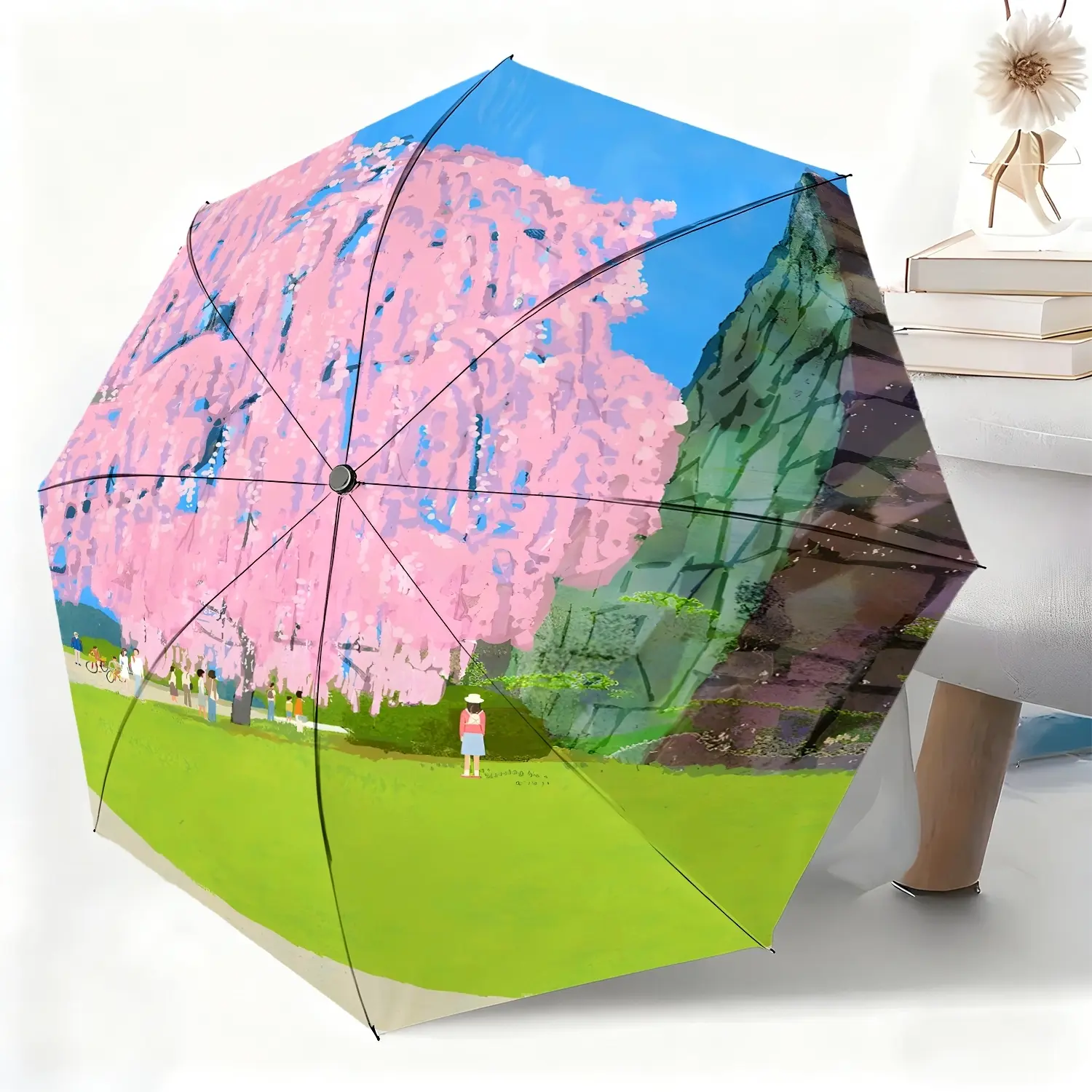 A waterproof folding umbrella featuring a spring scene of pink cherry blossoms and crowds, suitable for both men and women, and portable for travel and everyday use.