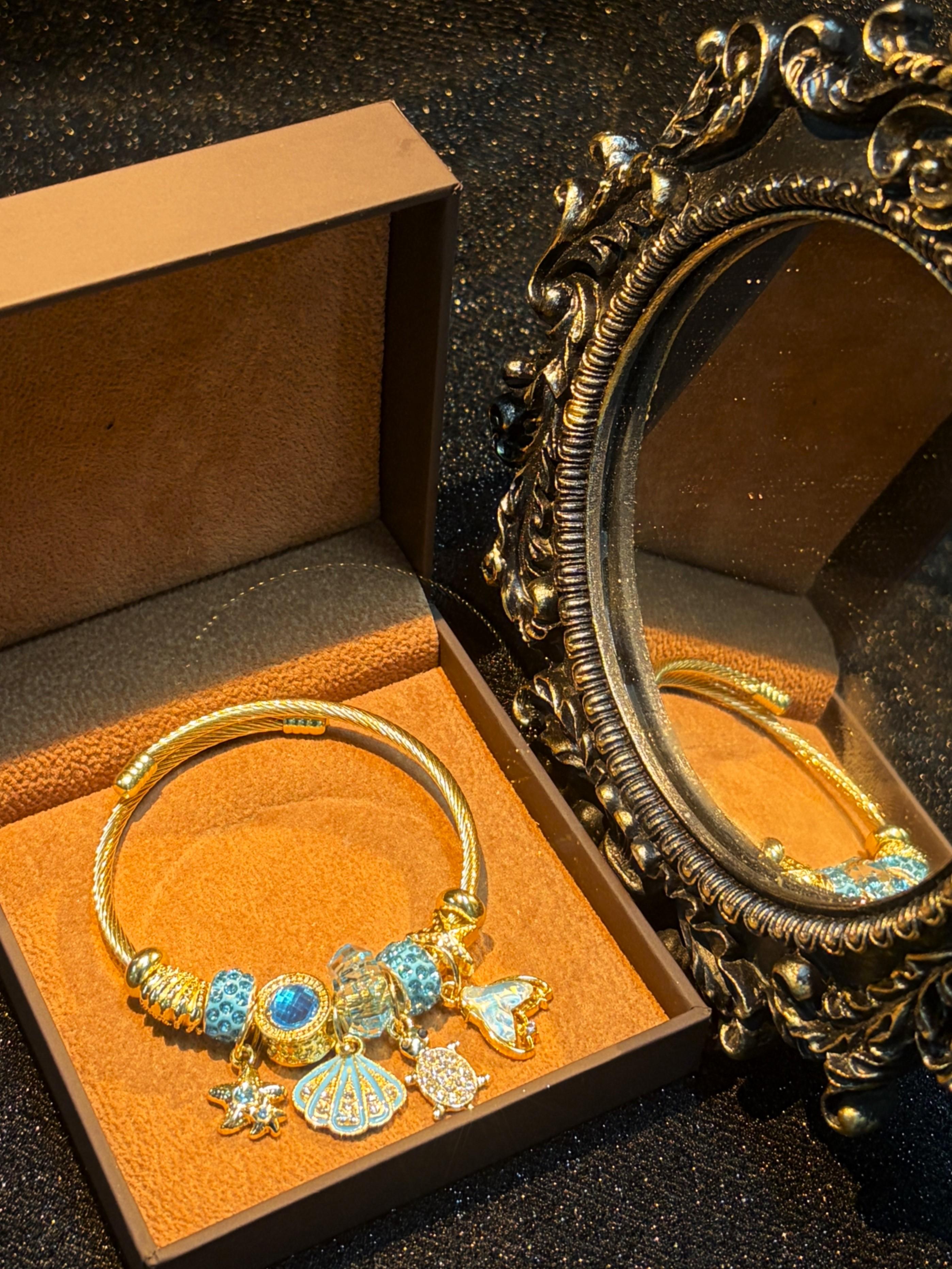 Women's Gold-Tone Ocean Theme Charm Bangle - Sea Shell, Turtle, Starfish, Mermaid Tail Accents with Sparkling Blue Crystal Beads Women's Gold-Tone Ocean Theme Charm Bangle - Sea Shell, Turtle, Starfish, Mermaid Tail Accents with Sparkling Blue Crystal Beads