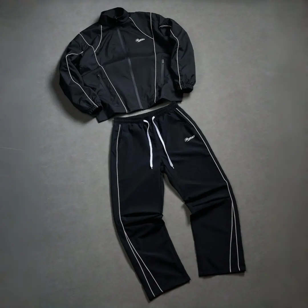 Men’s two-piece set: black jacket with contrasting lines and a stand collar, paired with wide-leg pants. Relaxed street casual style with evenly spaced white lines for a structured look. Jacket features elastic cuffs to maintain shape, while pants have a