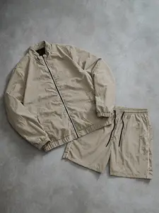 Retro minimalist khaki two-piece athletic set featuring a windproof textured fabric jacket and breathable, moisture-wicking quick-dry shorts. The complete outfit has a relaxed, loose fit suitable for afternoon strolls in the city, casual coffee dates, and
