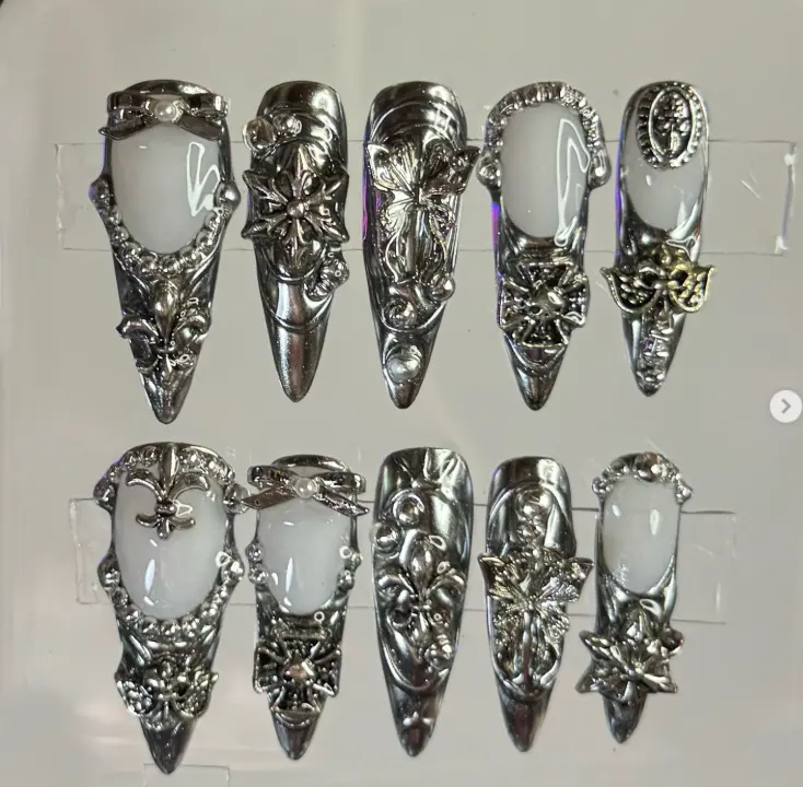 Fierce metallic silver nails with bold 3D embellishments and intricate gothic details, creating a dramatic and high-fashion statement look