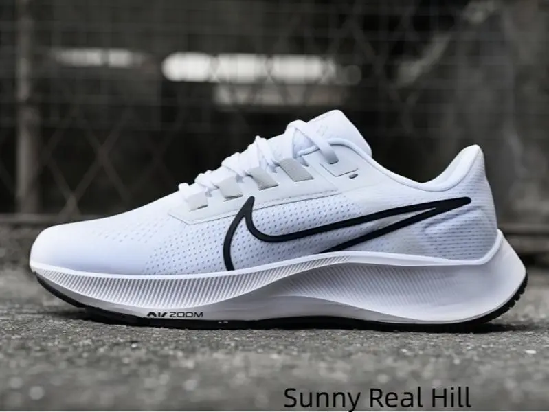 Crisp plain white athletic shoes with sleek black logo detailing deliver soft stable cushioning for subway commutes, grocery shopping and scattered small errands around dense urban residential blocks each weekday