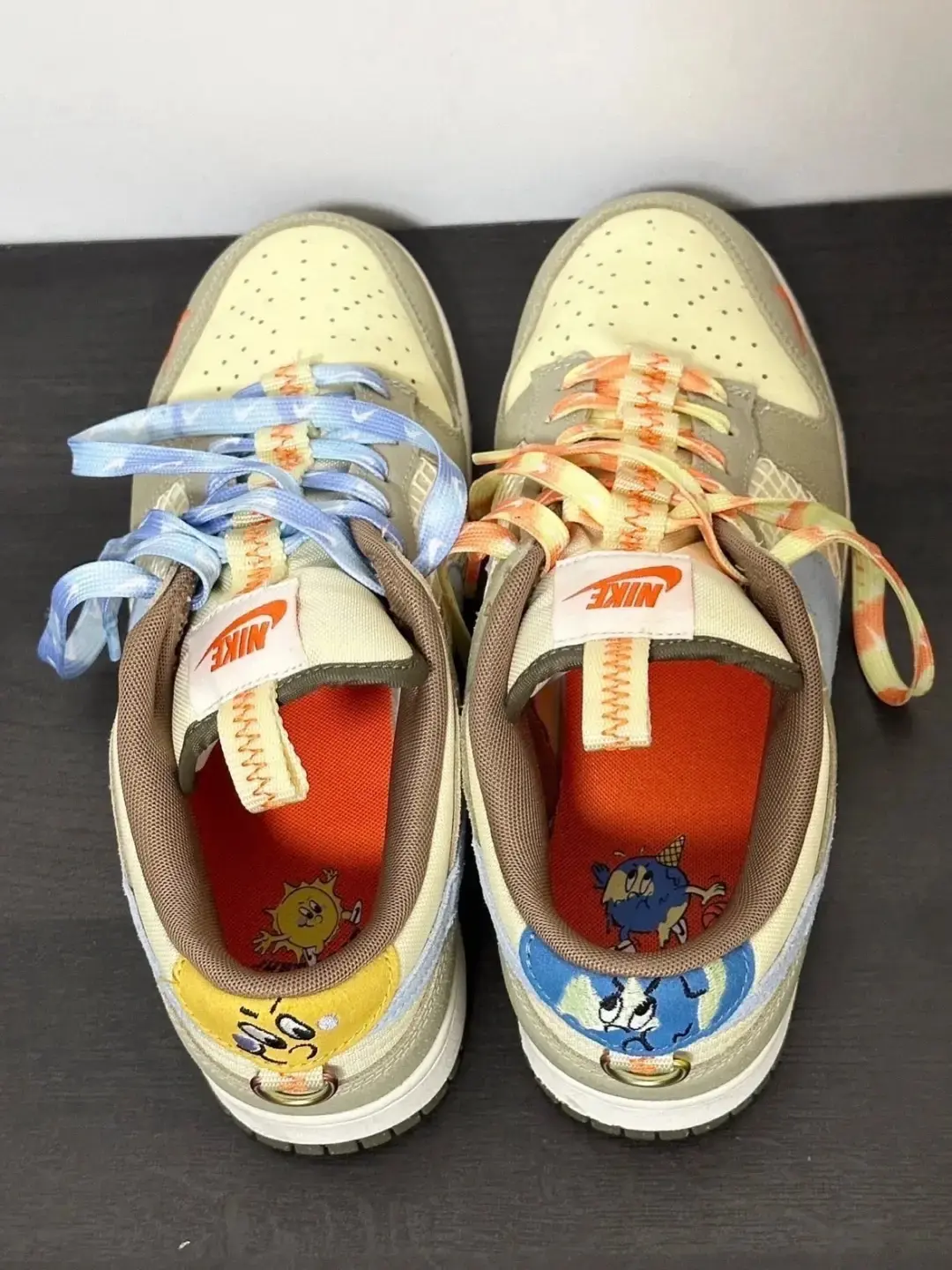 Mixed‑material low‑top skate kicks, cream khaki base with blue accents, contrast colorful laces, stitched detailing, flat rubber sole for street‑wear scenes