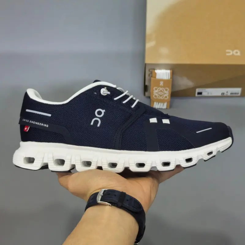 Retro running sneakers with flexible segmented shock-absorbing athletic silhouette, premium breathable knit mesh finished in deep navy blue paired with crisp white shoelace accents, hollow cushioned foam midsole