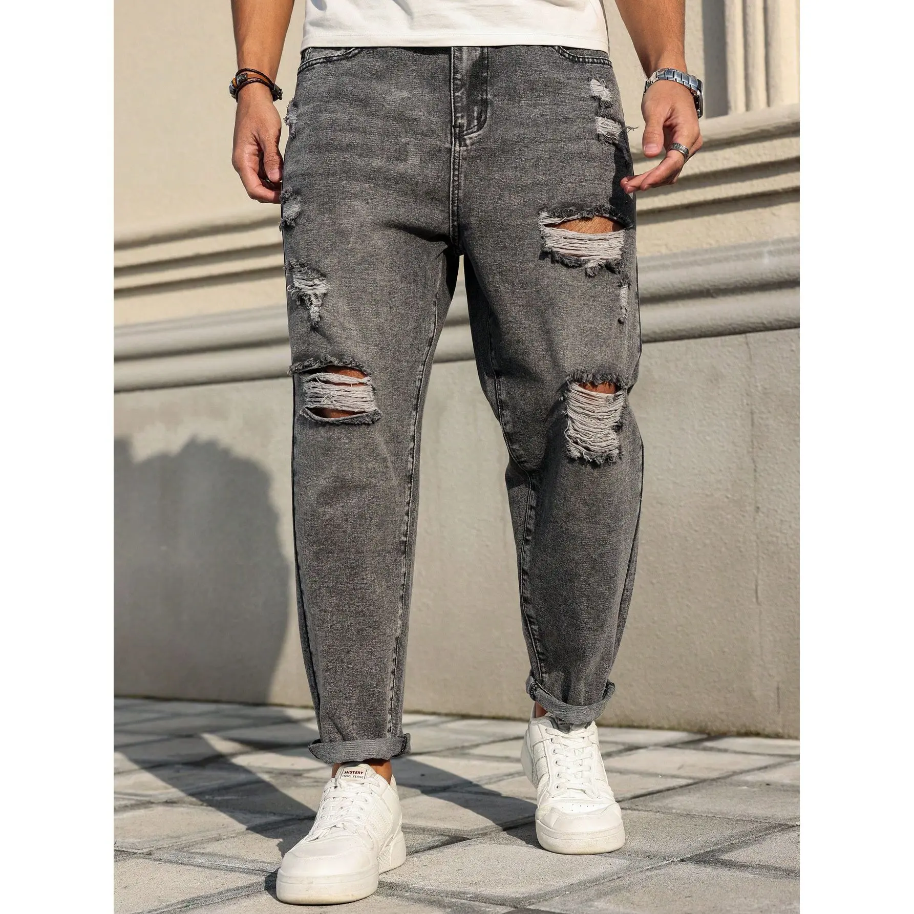 One piece men’s harem jeans in smoke gray with distressed rips; urban casual style. Mid rise button design paired with a washed distressed finish and large ripped frayed hems. Denim fabric drapes comfortably. Suitable for city men’s everyday commuting, ca